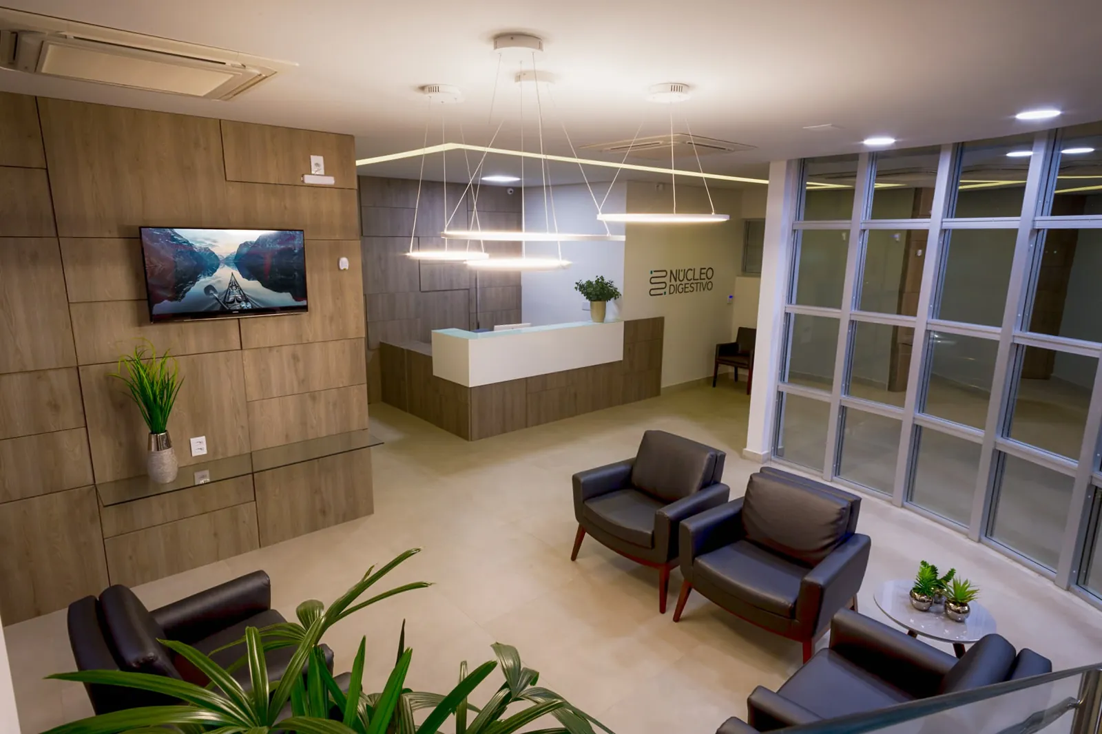 Recepção do Núcleo Digestivo, com balcão branco, painel de madeira e poltronas de espera